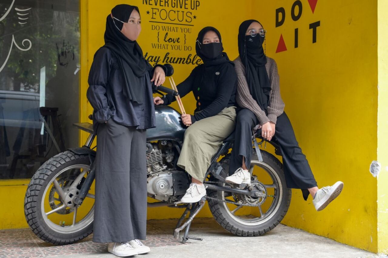 En esta foto tomada el 16 de abril de 2021, los miembros de la banda indonesia de heavy metal Voice of Baceprot (VOB), la bajista Widi Rahmawati (izq.), la baterista Euis Siti Aisah (c) y la guitarrista y vocalista Firda Marsya Kurnia (der.) posan durante una entrevista en Yakarta. Foto de Bay Ismoyo / AFP