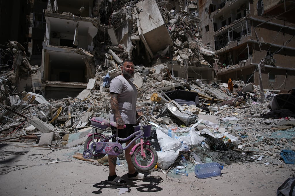 El barbero Wissam Srour, de 41 años, sostiene la bicicleta de su hija, recuperada de su barbería, mientras busca pertenencias entre los escombros del local, dañado por un ataque israelí, en la ciudad portuaria de Tiro, Líbano, el viernes 19 de junio de 2026.