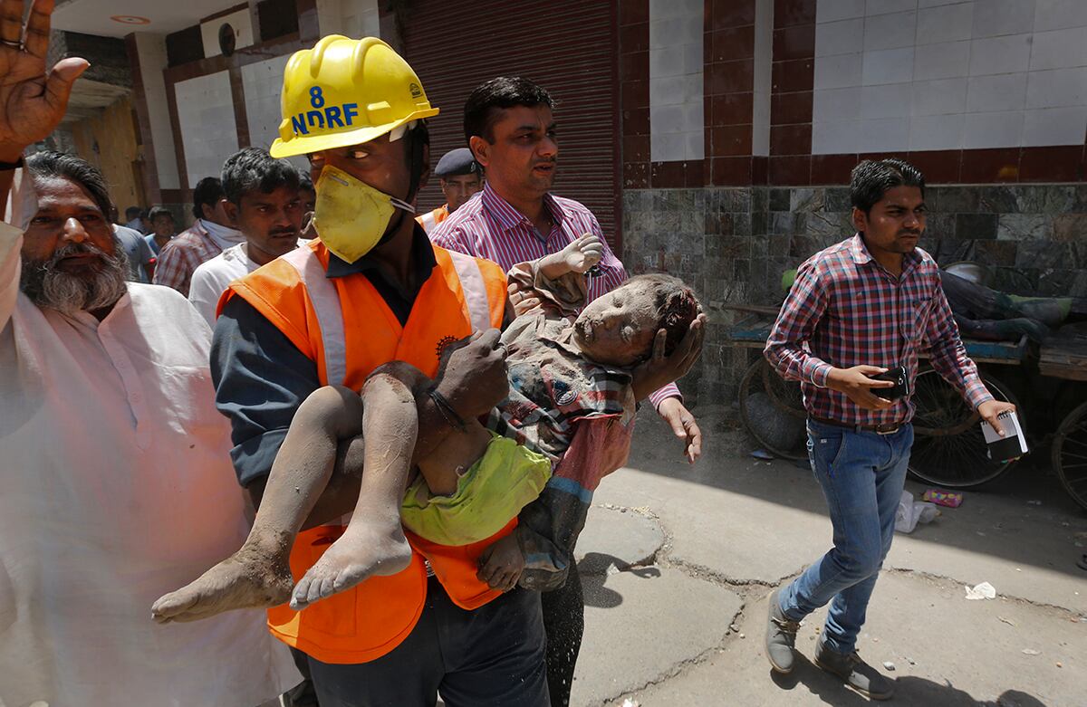 Un miembro de la Fuerza Nacional de Respuesta a Desastres carga a un niño herido que fue encontrado bajo los escombros de un edificio residencial que colapsó luego de la explosión de un cilindro de gas, en Nueva Delhi, India. (AP)