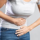 Mujer joven con dolor de estómago doloroso. Gastritis crónica. Calambres estomacales o menstruales. Concepto de hinchazón abdominal.