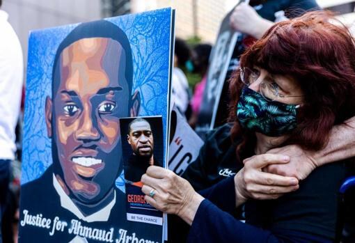 Una mujer sostiene las imágenes de Ahmaud Arbery y George Floyd durante un acto en Mineápolis en recuerdo a los ambos asesinados AFP