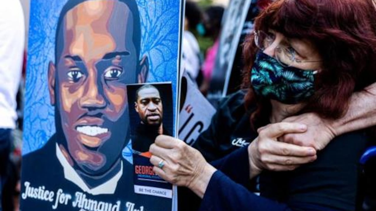 Una mujer sostiene las imágenes de Ahmaud Arbery y George Floyd durante un acto en Mineápolis en recuerdo a los ambos asesinados AFP
