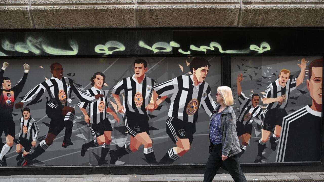Un peatón pasa frente a un mural con el tema del club de fútbol del Newcastle United en Newcastle upon Tyne, en el noreste de Inglaterra, el 8 de octubre de 2021 (Photo by Oli SCARFF / AFP)