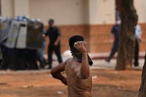 Un manifestante enmascarado termina para arrojar una piedra en enfrentamientos con la policía durante una protesta indígena contra un proyecto de ley que criminaliza las invasiones de tierras, frente al Congreso en Asunción, Paraguay, el miércoles 29 de septiembre de 2021. Si el proyecto de ley se aprueba, afectaría a varios indígenas comunidades que residen en asentamientos improvisados a la espera de la restitución de sus tierras. Foto AP / Jorge Saenz