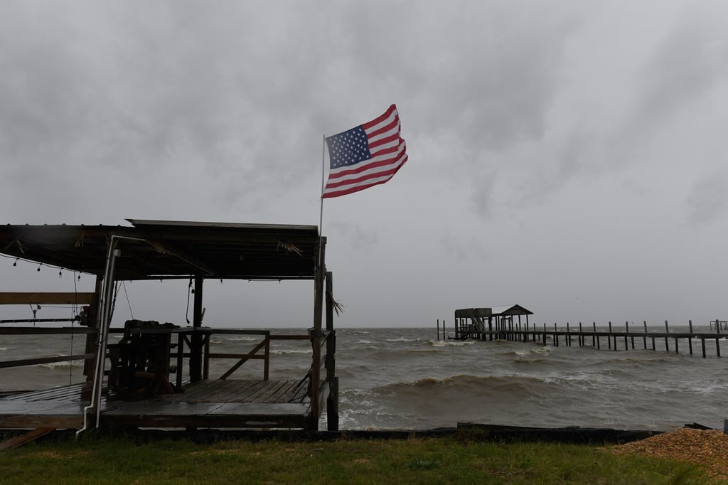 Una bandera estadounidense ondea al viento generado por los efectos de Isaías en una playa desierta el viernes 9 de octubre de 2026, en Mon Louis Island, Alabama. (Foto AP/Octavio Jones)