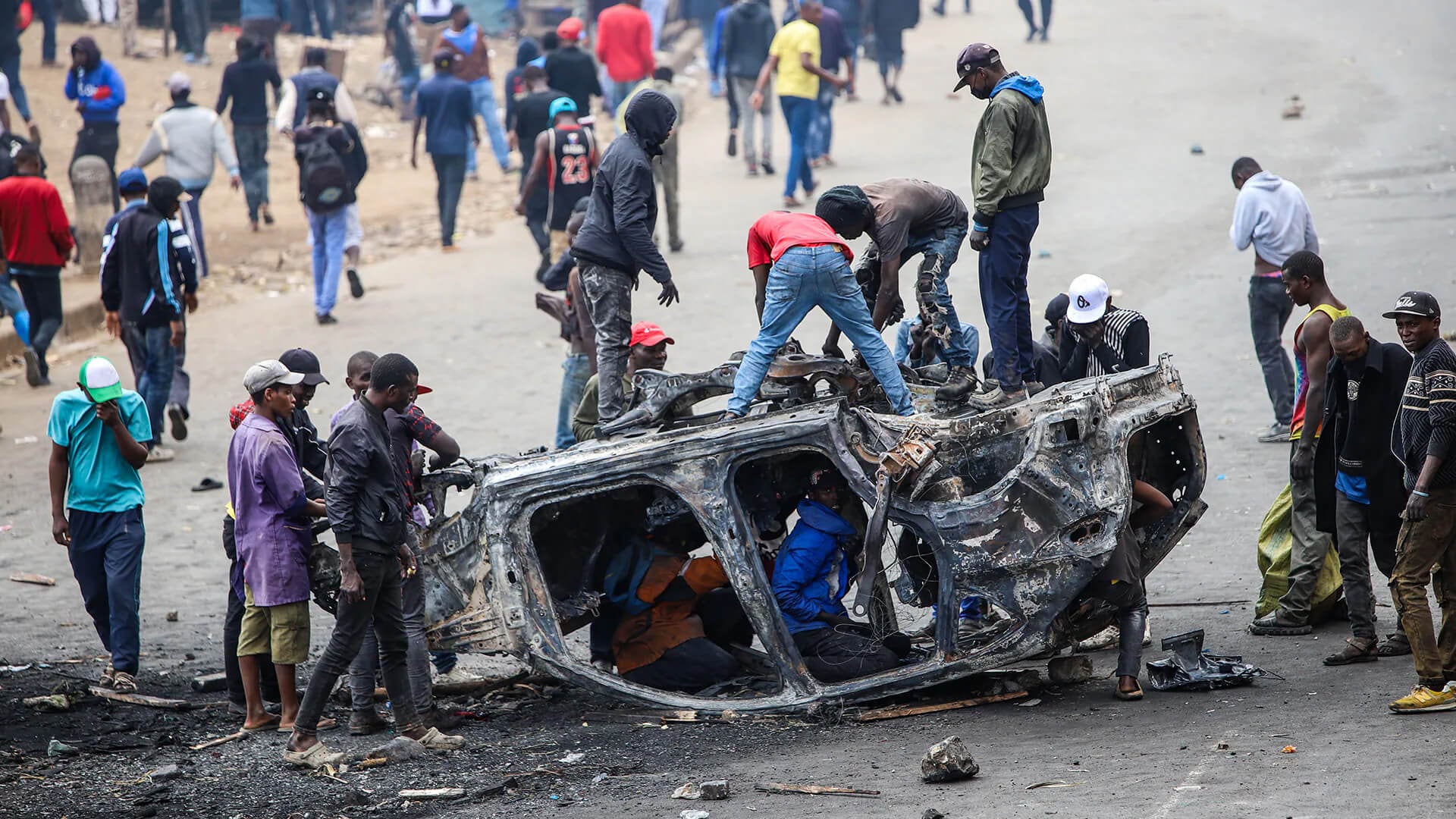 Personas retiran piezas de un vehículo incendiado durante una huelga de transporte público por el aumento de los precios del combustible en Nairobi, Kenia, el lunes 18 de mayo de 2026.