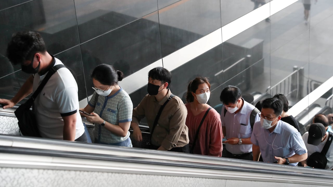Las personas que usan máscaras faciales toman las escaleras mecánicas en la estación Yongsan en Seúl, Corea del Sur