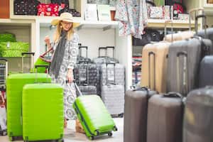 Joven comprando una maleta en preparación para las vacaciones