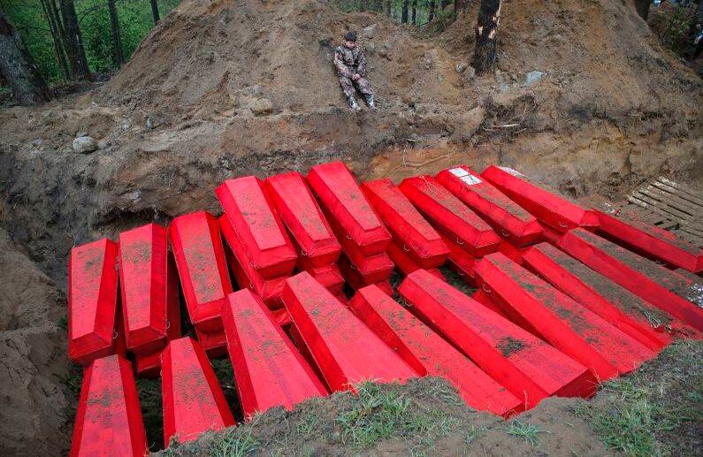 Un niño, miembro de un equipo de búsqueda de voluntarios, se sienta cerca de una fosa común con ataúdes con los restos de soldados soviéticos asesinados durante la Segunda Guerra Mundial, durante una ceremonia de entierro en el monumento a las alturas de Sinyavino al este de San Petersburgo, Rusia. FOTO: Dmitri Lovetsky / AP