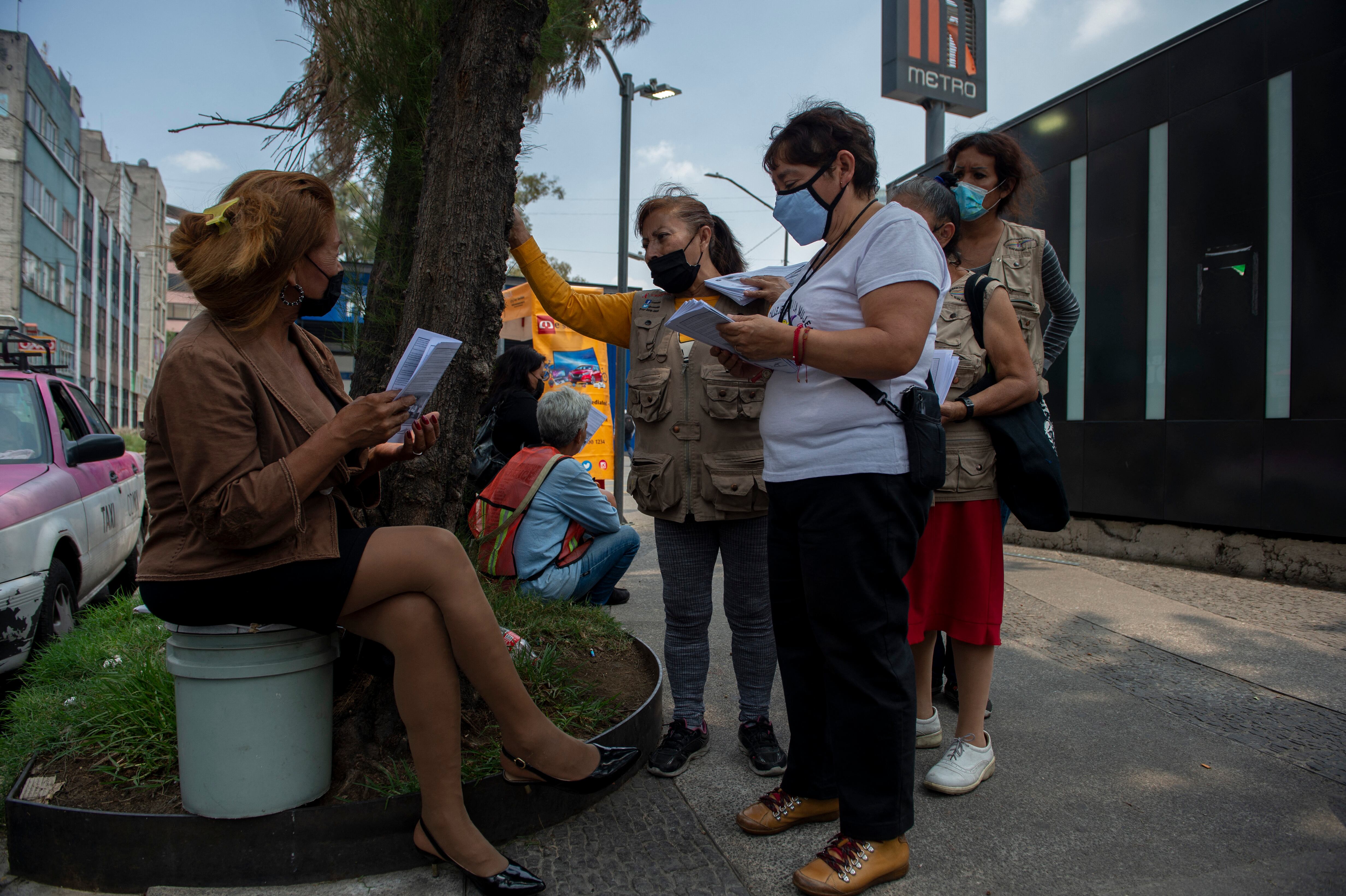 Members of the NGO Elisa Mart�nez Street Brigade in Support of Woman, give a copy of the newspaper �Noticalle� to a sex worker in Mexico City, on June 30, 2022. - Women -mostly sex workers- write for a free monthly magazine called Noticalle published by the non-governmental organization Brigada Callejera (Street Brigade) to decry injustices. (Photo by CLAUDIO CRUZ / AFP)