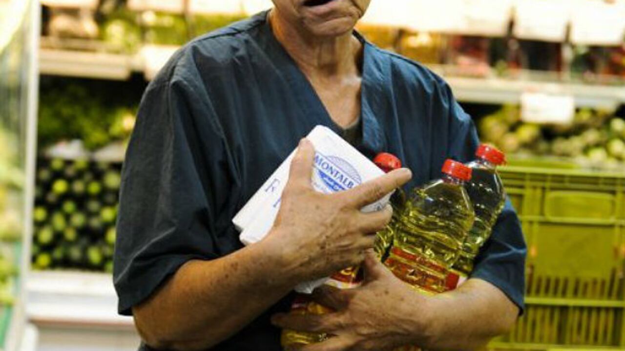 Una mujer carga su compra en un mercado de Caracas.