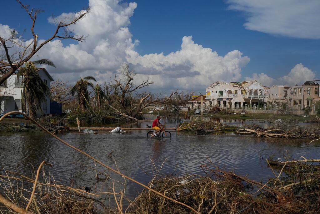 Un hombre circula en bicicleta por una calle inundada de Black River, Jamaica, el jueves 30 de octubre de 2025, tras el paso del huracán Melissa. (Foto AP/Matias Delacroix)