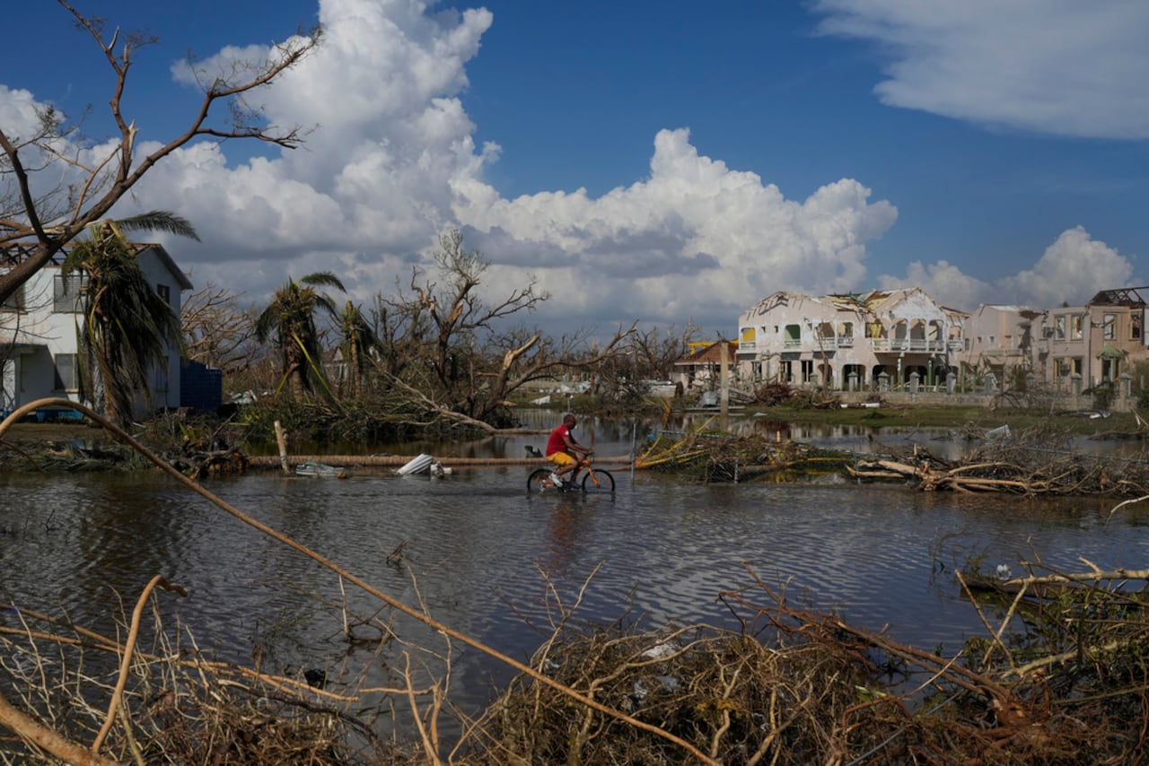 Un hombre circula en bicicleta por una calle inundada de Black River, Jamaica, el jueves 30 de octubre de 2025, tras el paso del huracán Melissa. (Foto AP/Matias Delacroix)