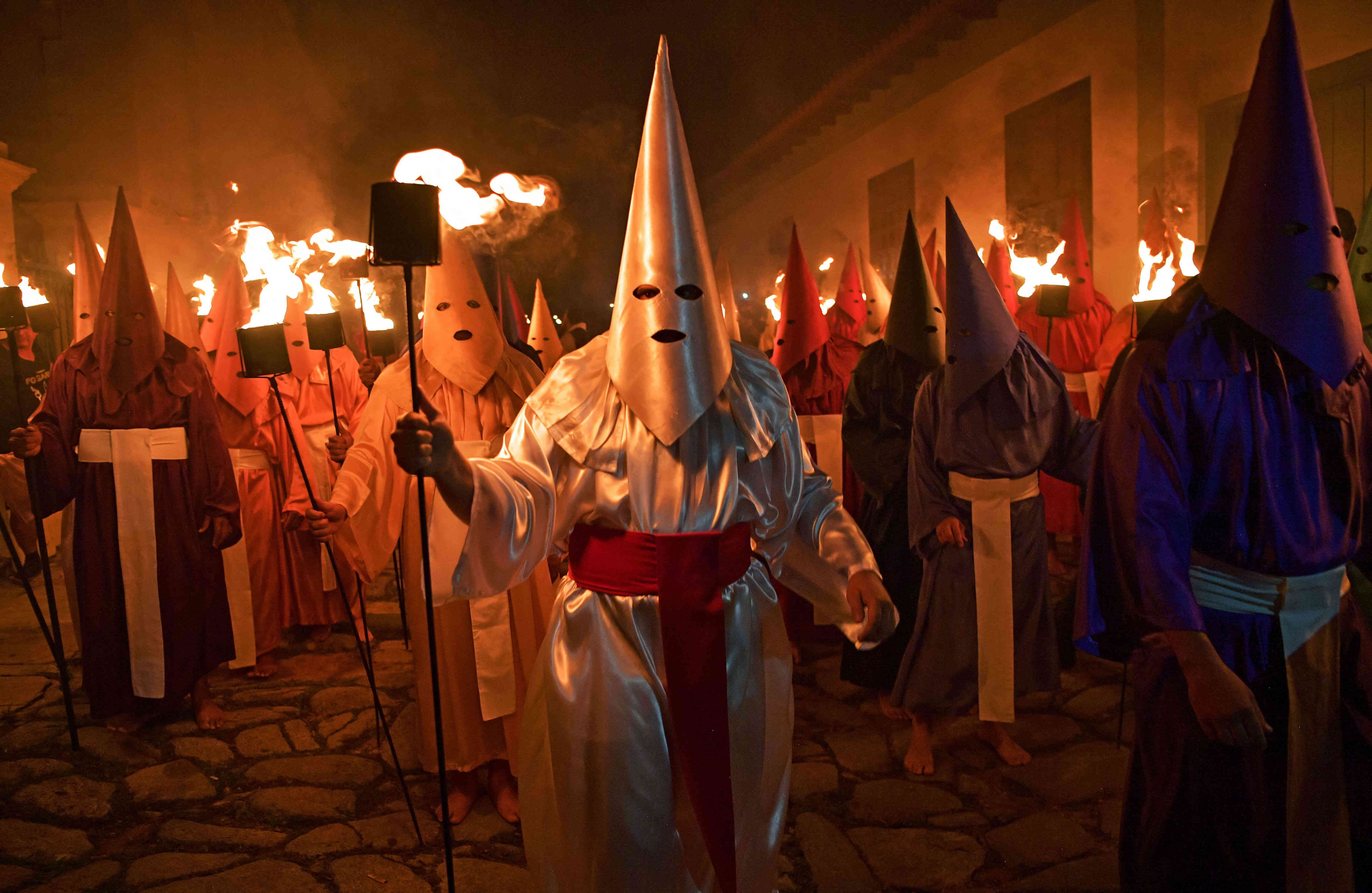 Fieles católicos encapuchados que representan a los soldados romanos, conocidos como Farricocos, llevan antorchas encendidas durante la procesión anual de la Semana Santa de Fogareu en Goias, 350 km al oeste de Brasilia, Brasil, a principios del 18 de abril de 2019. Los trajes son de origen medieval, y fueron utilizados por los penitentes para que pudieran expiar sus pecados sin tener que revelar su identidad en público. CARL DE SOUZA / AFP