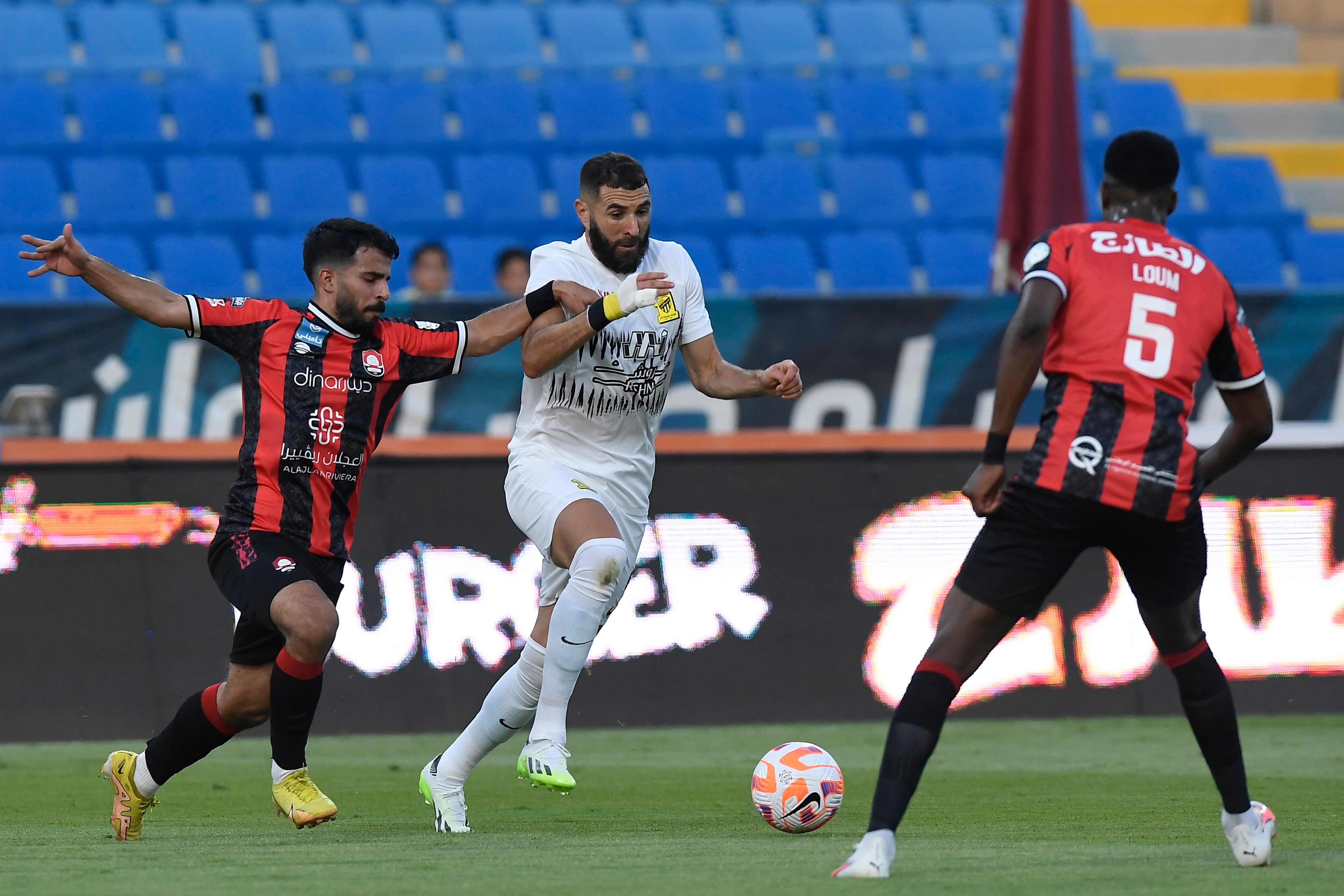 Al Ittihad's Karim Benzema, center, fights for the ball during his team match against Al Raed in Saudi Professional League, in Buraidah, Saudi Arabia, Monday, Aug. 14, 2023. (AP Photo)