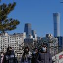 People wearing face masks to help protect from the coronavirus walk by lantern decorations for the upcoming Lunar New Year in a park seen against the city skyline in Beijing, Thursday, Jan. 27, 2022. (AP Photo/Andy Wong)