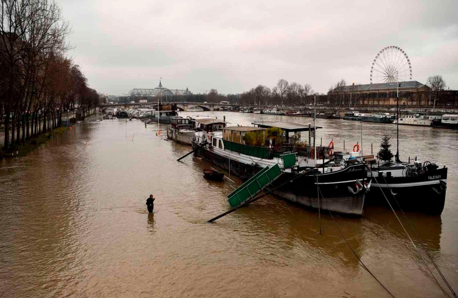 Un hombre camina hacia una barcaza en el río Sena después de que estalló.  Se espera que el Sena alcance 6,2 metros (20,3 pies), el 27 de enero de 2018, un punto máximo alcanzado en 2016 cuando las inundaciones enviaron museos ribereños luchando para mover obras de arte de sus sótanos, que era el nivel más alto desde 1982. / AFP PHOTO / Christophe Simon.