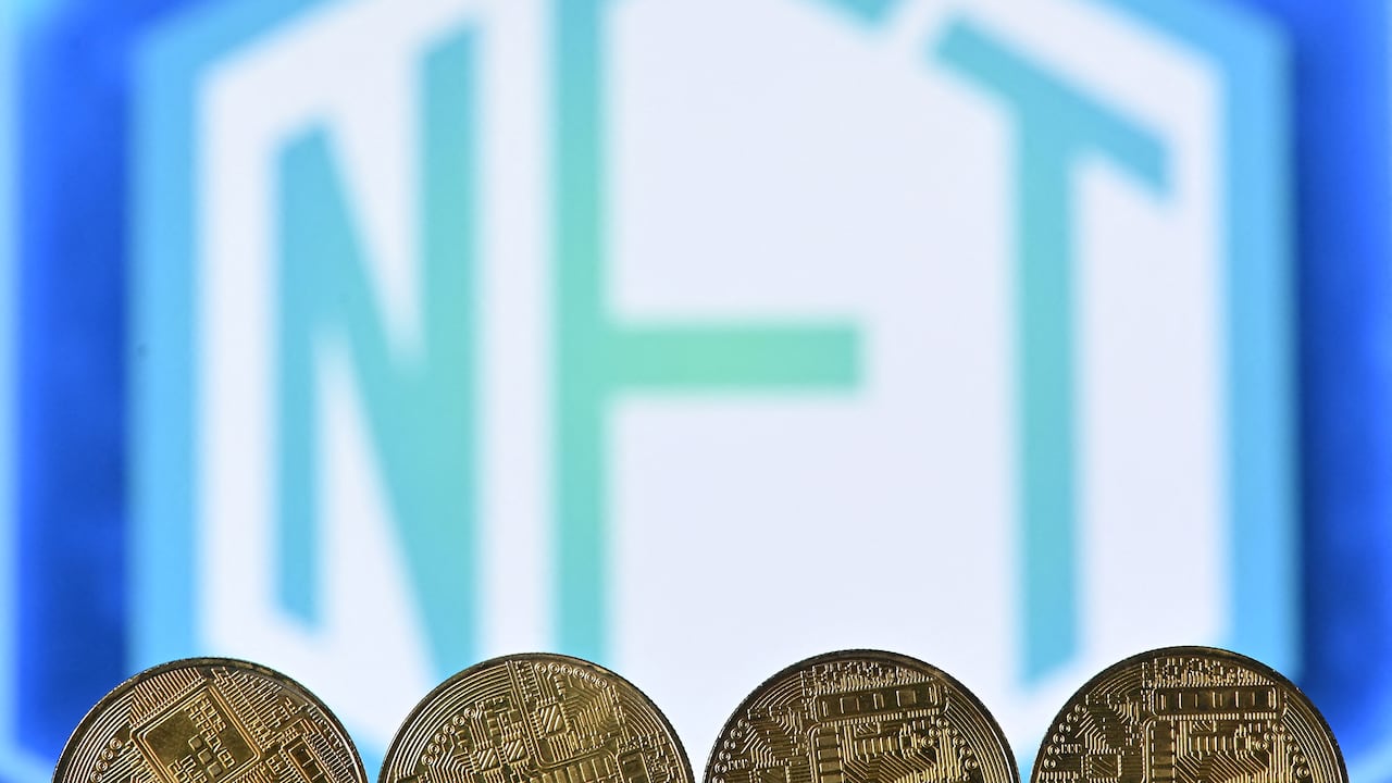 Esta foto de archivo tomada el 30 de diciembre de 2021 muestra una imagen ilustrativa tomada en Londres de monedas de criptomoneda de recuerdo chapadas en oro dispuestas por una pantalla que muestra un logotipo NFT (token no fungible).
Justin TALLIS / AFP
