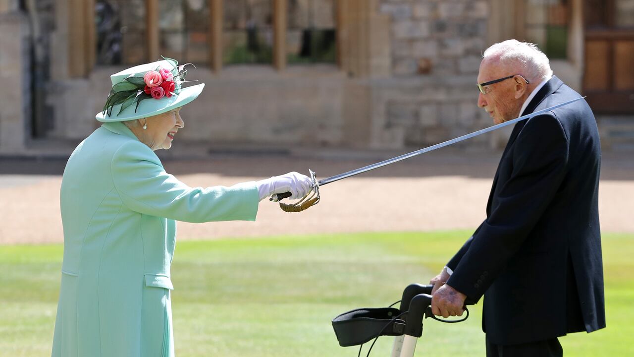 (FILES) In this file photo taken on July 17, 2020 Britain's Queen Elizabeth II uses the sword that belonged to her father, George VI as she confers the Honour of Knighthood on 100-year-old WWII veteran Captain Tom Moore at Windsor Castle in Windsor, west of London on July 17, 2020. - Britain's lockdown hero, Captain Tom Moore has died at the age of 100 after testing positive for Covid-19. The charity fundraiser was taken to Bedford Hospital on Sunday after testing positive for coronavirus last week. (Photo by Chris Jackson / POOL / AFP)