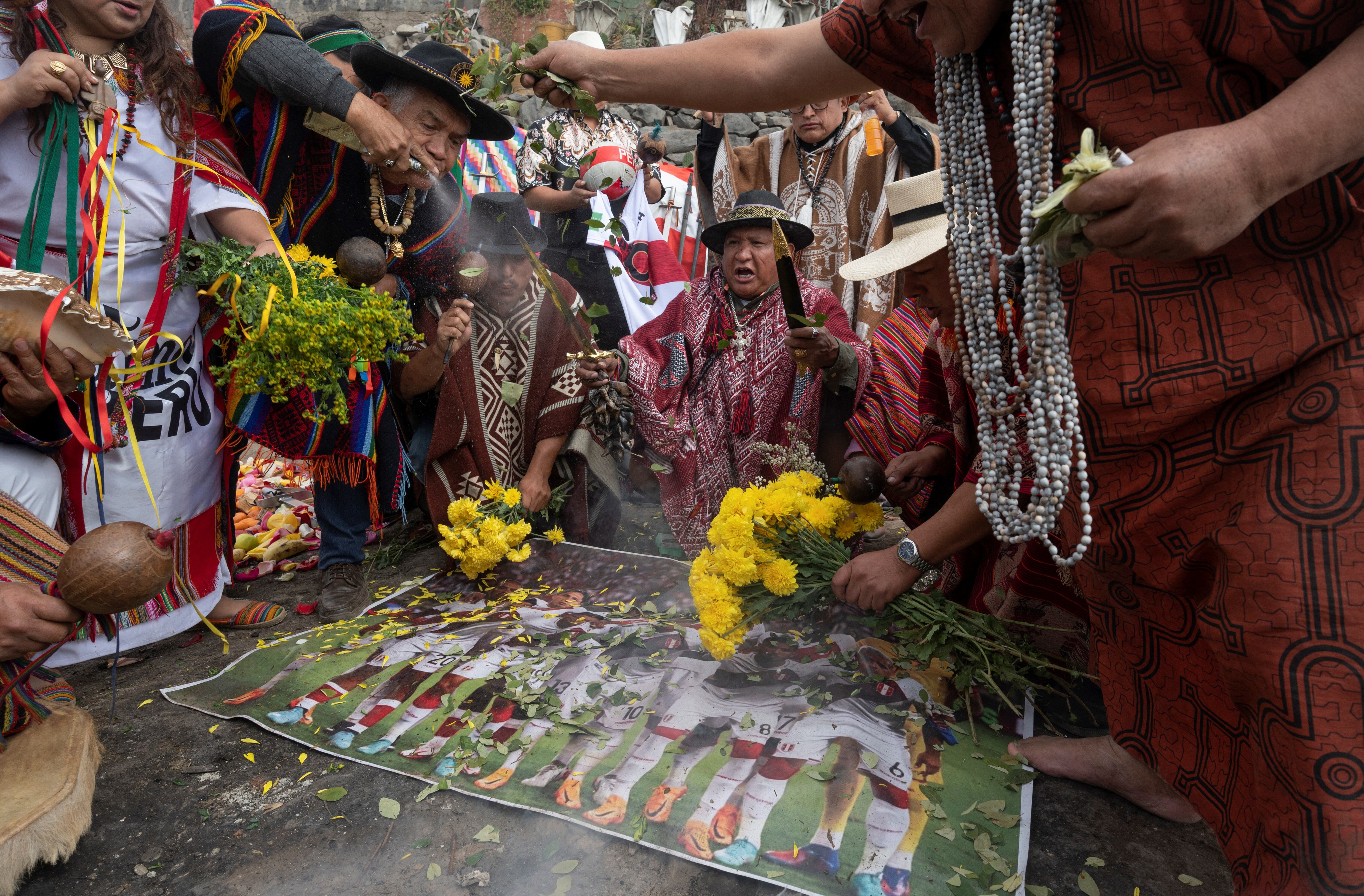 Peruvian shamans perform a ritual in Lima on June 10, 2022, offering flower petals, coca leaves and fruit in favor of the Peruvian football team and throwing spells and curses against the Australian football team, ahead of the FIFA World Cup Qatar 2022 playoff match next June 13. (Photo by Cris BOURONCLE / AFP)