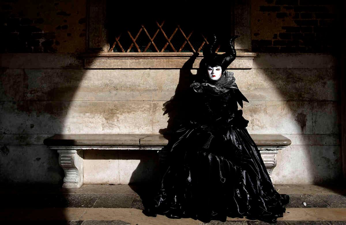 Una mujer vestida con un disfraz de carnaval se sienta en un banco del Palacio Ducal de Venecia, durante las celebraciones de carnaval en Venecia, Italia, el 16 de febrero de 2020. El carnaval de Venecia, en la histórica ciudad de la laguna, atrae a gente de todo el mundo. Foto: Luca Bruno/ AP.