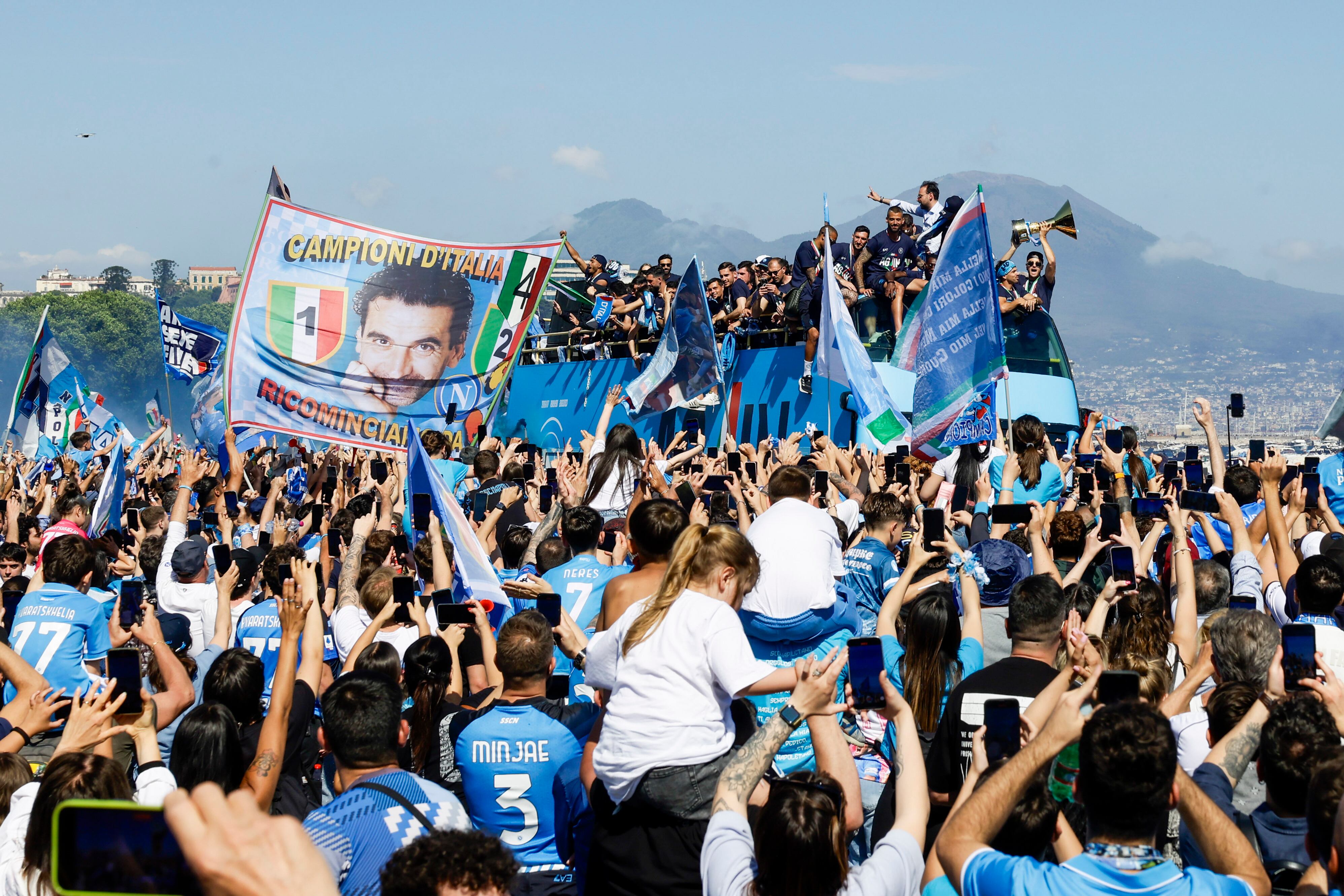 The crowd cheers as Napoli players celebrate winning their fourth Serie A soccer league title in an open-air bus parade alongside Naples' seafront, with Mt. Vesuvius in the background, Italy, Monday, May 26, 2025. (Antonio Balasco/LaPresse via AP)