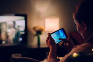 Woman using mobile app at home in front of tv.
