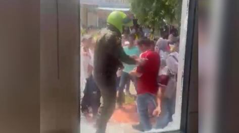 Un policía tratando de impedir que el sujeto de rojo lanzara los que serían los fósforos contra la sede de la Registraduría en Gamarra, que había sido rociada con gasolina.