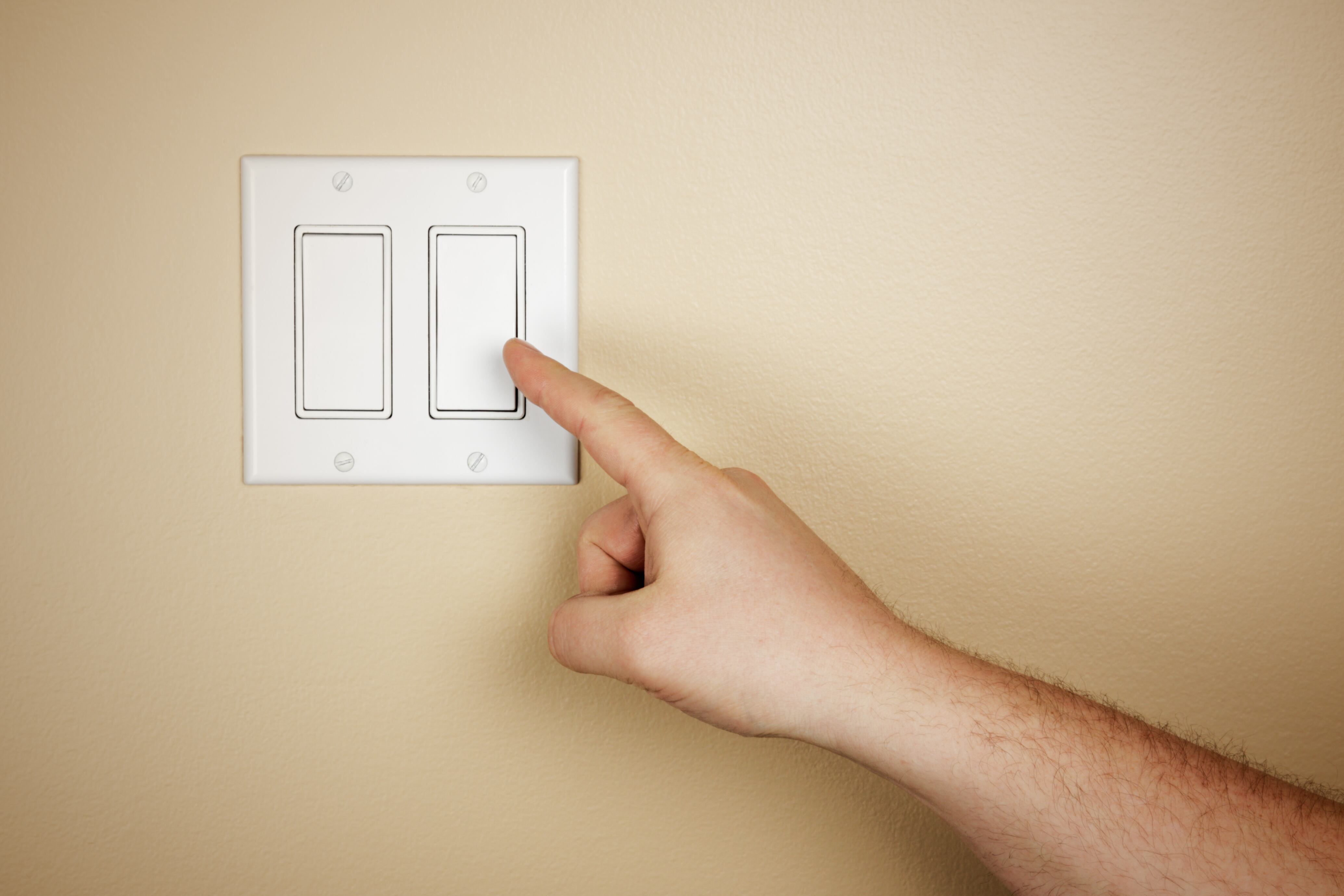 Una mano masculina se mueve para apagar un interruptor de luz.