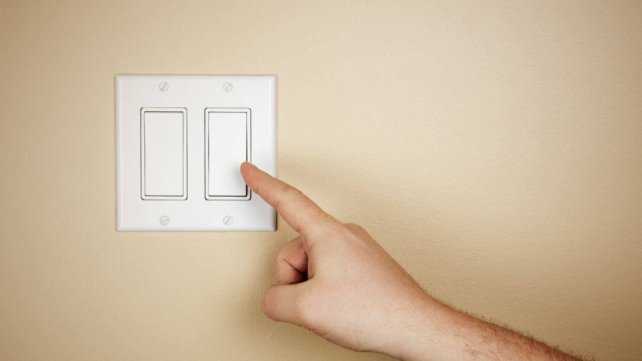 Una mano masculina se mueve para apagar un interruptor de luz.