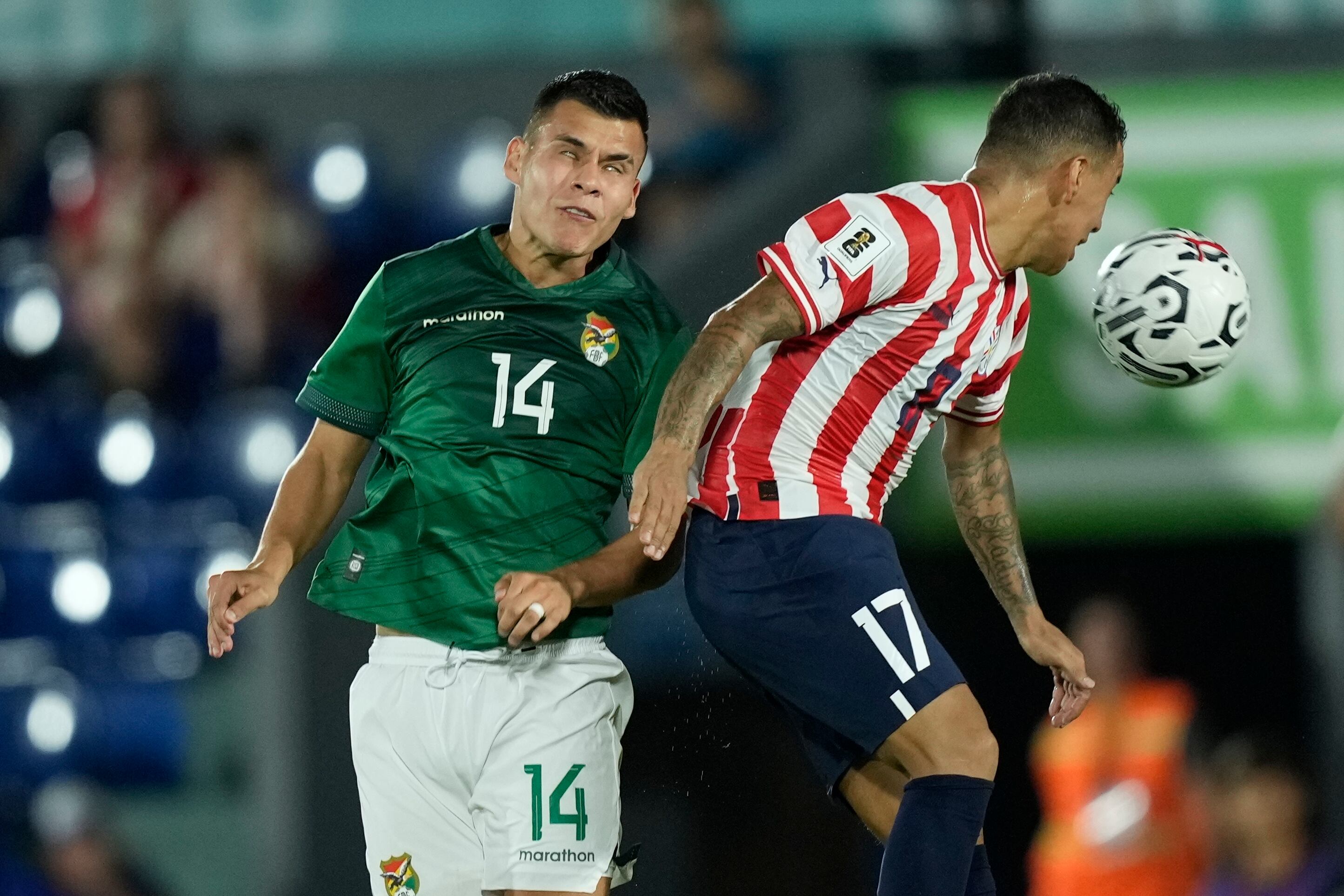 El boliviano Moisés Villarroel, izquierda, busca un cabezazo con el paraguayo Alejandro Romero durante un partido de fútbol de clasificación para la Copa Mundial de la FIFA 2026, en el Estadio Defensores del Chaco en Asunción, Paraguay, el martes 17 de octubre de 2023. (AP Foto/Jorge Saenz )