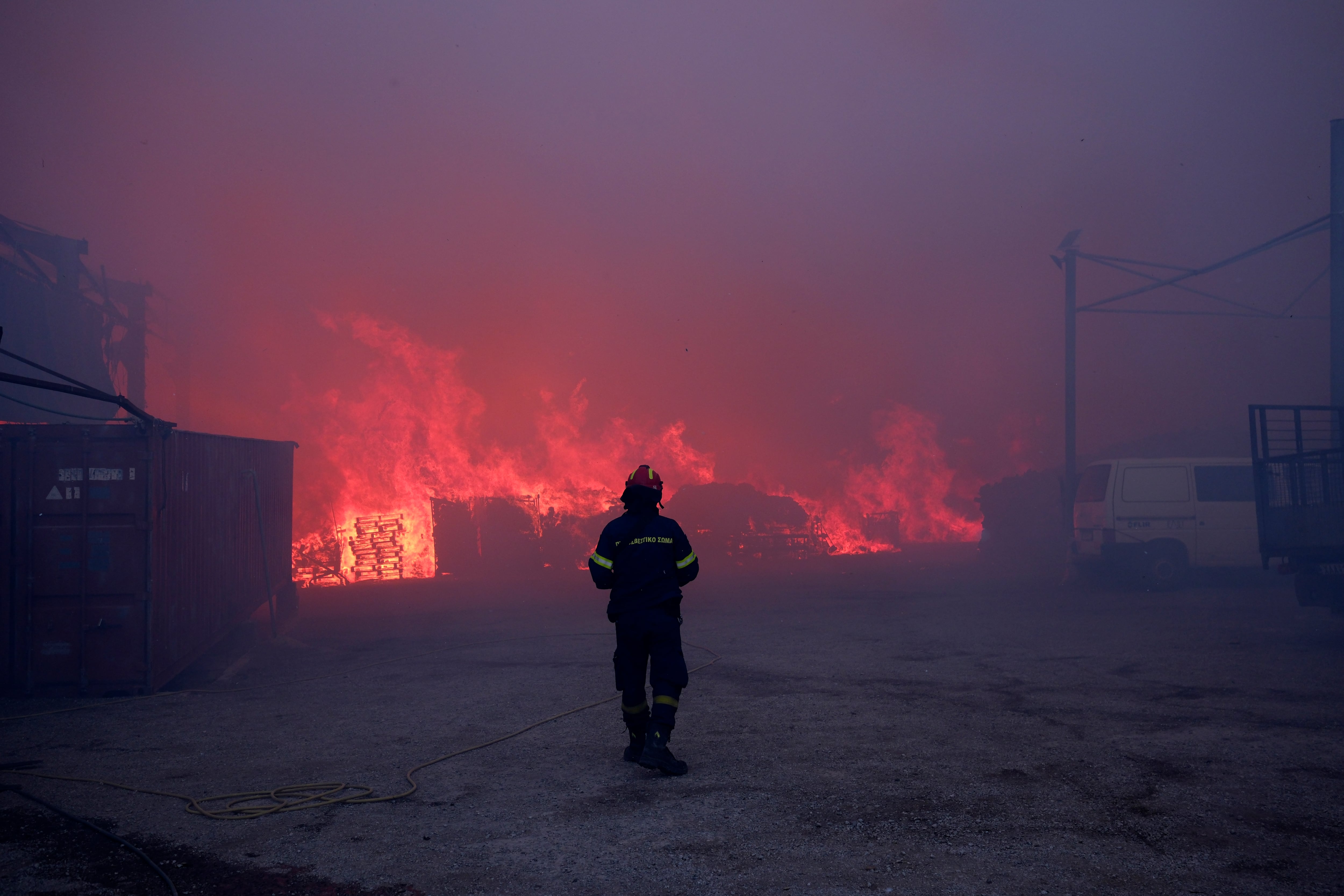 Un bombero observa las llamas en negocios que arden durante un incendio al norte de Atenas, el lunes 12 de agosto de 2024. (AP Foto/Aggelos Barai)