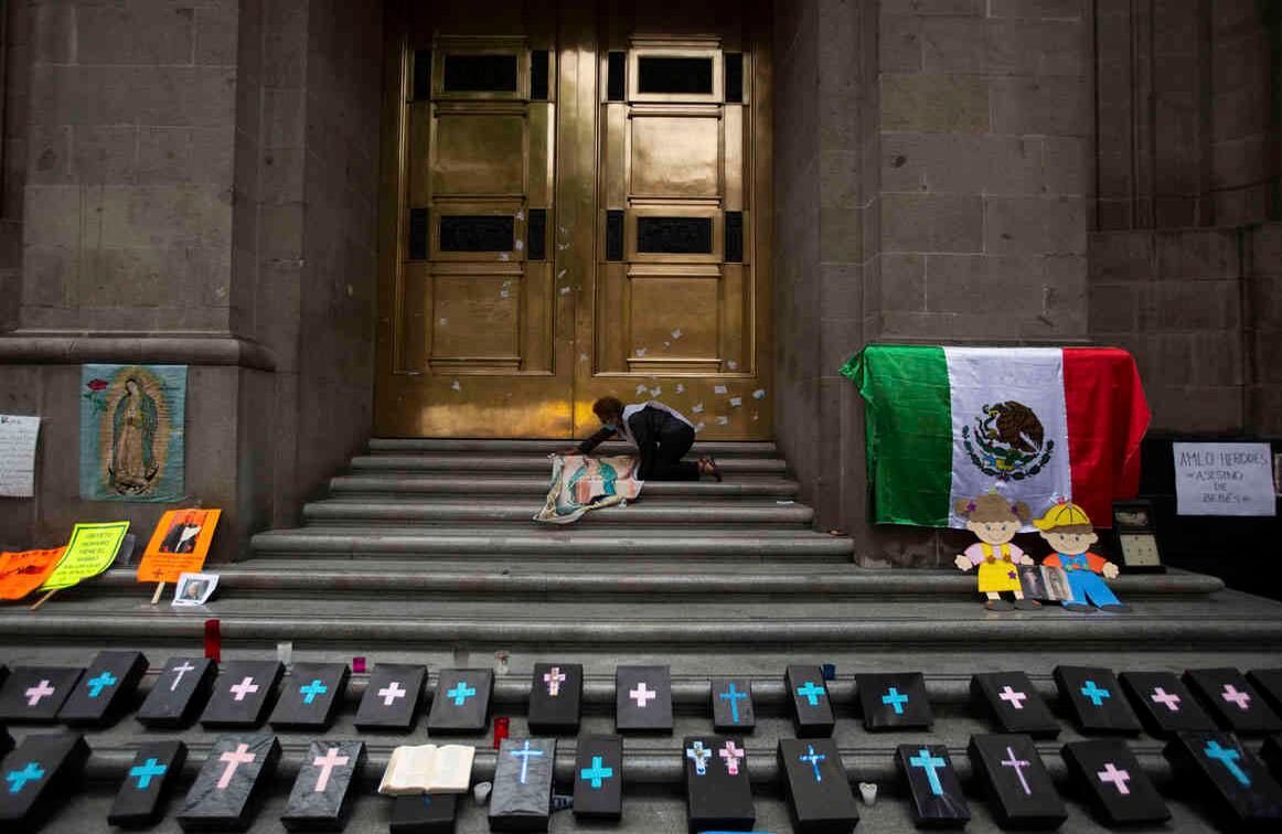 Una activista contra el aborto pone una imagen de la virgen de Guadalupe junto a pequeños ataúdes en la entrada de la Corte Suprema, para celebrar la decisión contra una orden judicial en el estado de Veracruz que tenía como objetivo despenalizar el aborto para todos los casos dentro de las primeras 12 semanas de embarazo. Dos de los 32 estados de México han despenalizado el aborto. Foto: Fernando Llano / AP