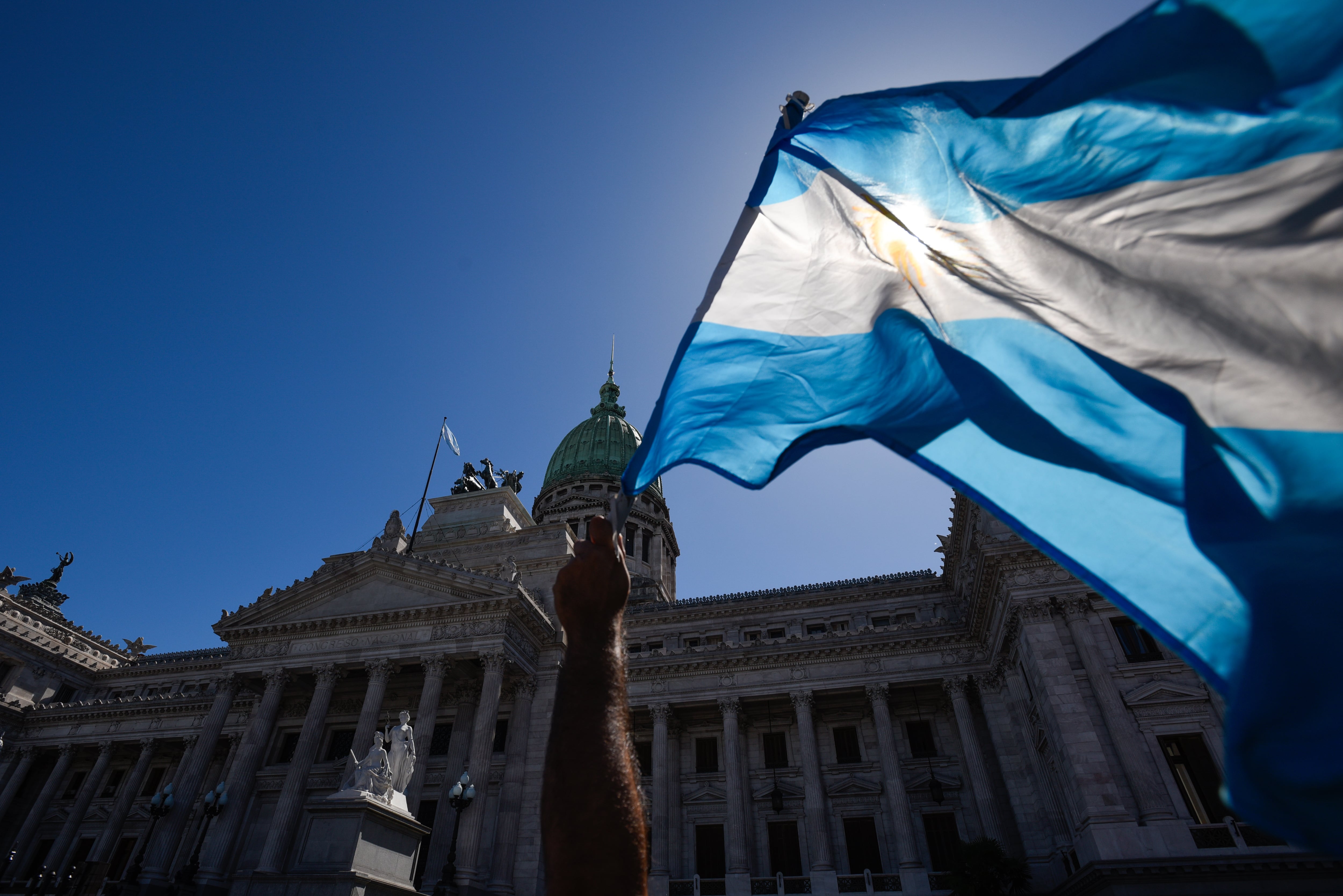 Un manifestante ondea la bandera argentina frente al Congreso durante una protesta contra los planes de reforma del gobierno ultraliberal del Presidente Milei el día de una huelga general. Los sindicatos habían convocado la huelga general. Con una inflación del 211,4 por ciento, el nuevo gobierno quiere impulsar un programa radical de austerida