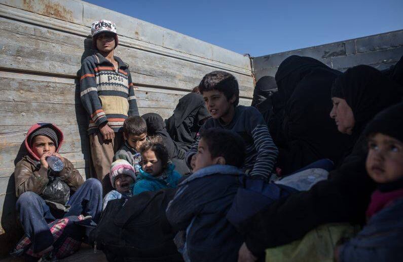 BAGOUZ, SIRIA - 12 DE FEBRERO: Los civiles que han huido de los combates en Bagouz esperan para abordar los camiones luego de ser examinados por miembros de las Fuerzas Democráticas de Siria (SDF) en un improvisado punto de detección en el desierto el 12 de febrero de 2019 en Bagouz, Siria.  FOTO: Chris McGrath / Getty Images