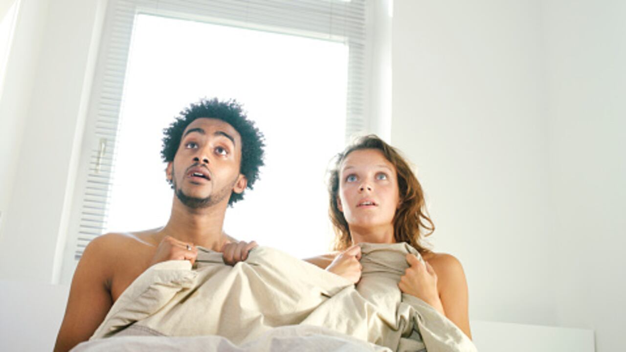 Foto ilustrativa de hombre y mujer en una cama, al parece teniendo relaciones cuando es visto por su esposa.