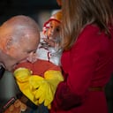 El presidente Joe Biden, en broma, muerde la pierna de un bebé, mientras él y la primera dama Jill Biden reciben a estudiantes del área local, niños relacionados con el ejército y familias del vecindario para pedir dulces, antes de Halloween el jueves, en el jardín sur del Casa Blanca en Washington el miércoles 30 de octubre de 2024. (Foto AP/Ben Curtis)