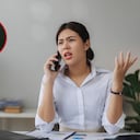 Mujer hablando por celular tras recibir una llamada spam.