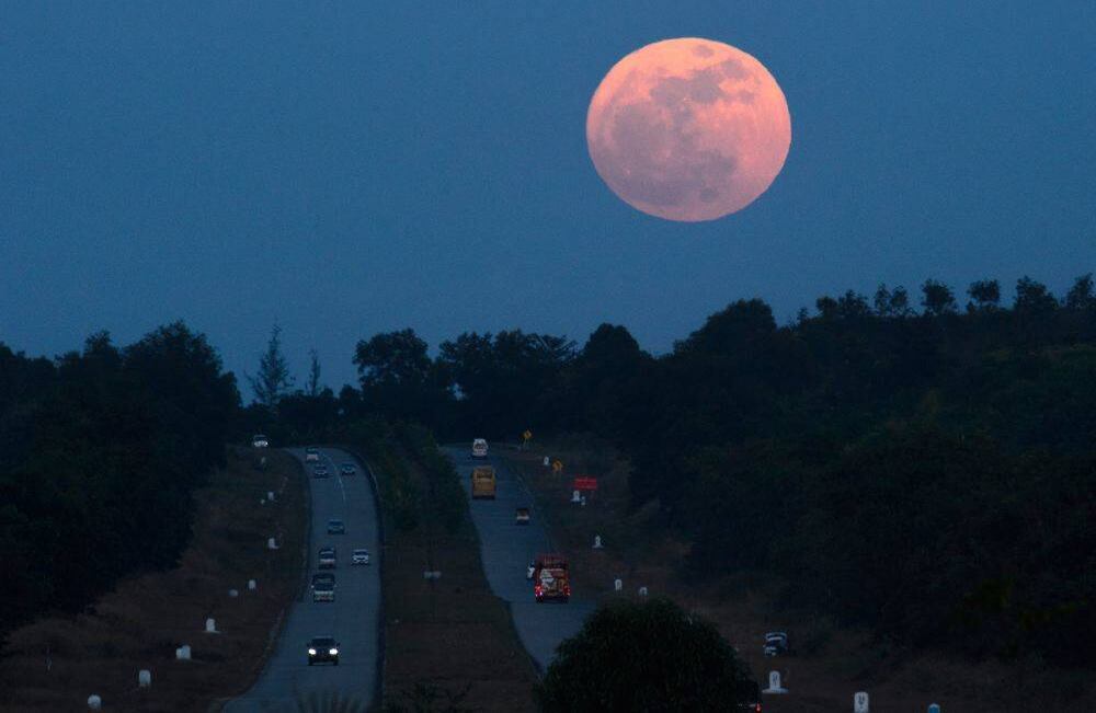 La superluna se eleva sobre una carretera cerca de Yangon el 3 de diciembre de 2017. El fenómeno lunar ocurre cuando una luna llena está en su punto más cercano a la tierra. / AFP PHOTO / Ye Aung THU 