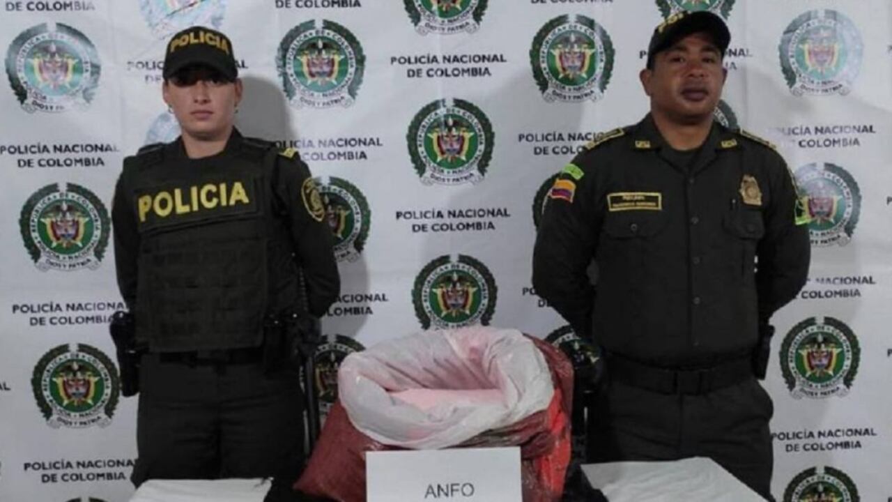 Uniformados de la Policía con el artefacto encontrado dentro de una caja de cartón en un bus de servicio público.