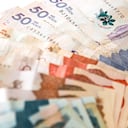 Macro primer plano de pesos colombianos de diferente valor en forma de abanico sobre un fondo blanco.