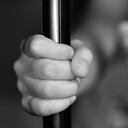 close up of a child's hand holding onto a metal bar.