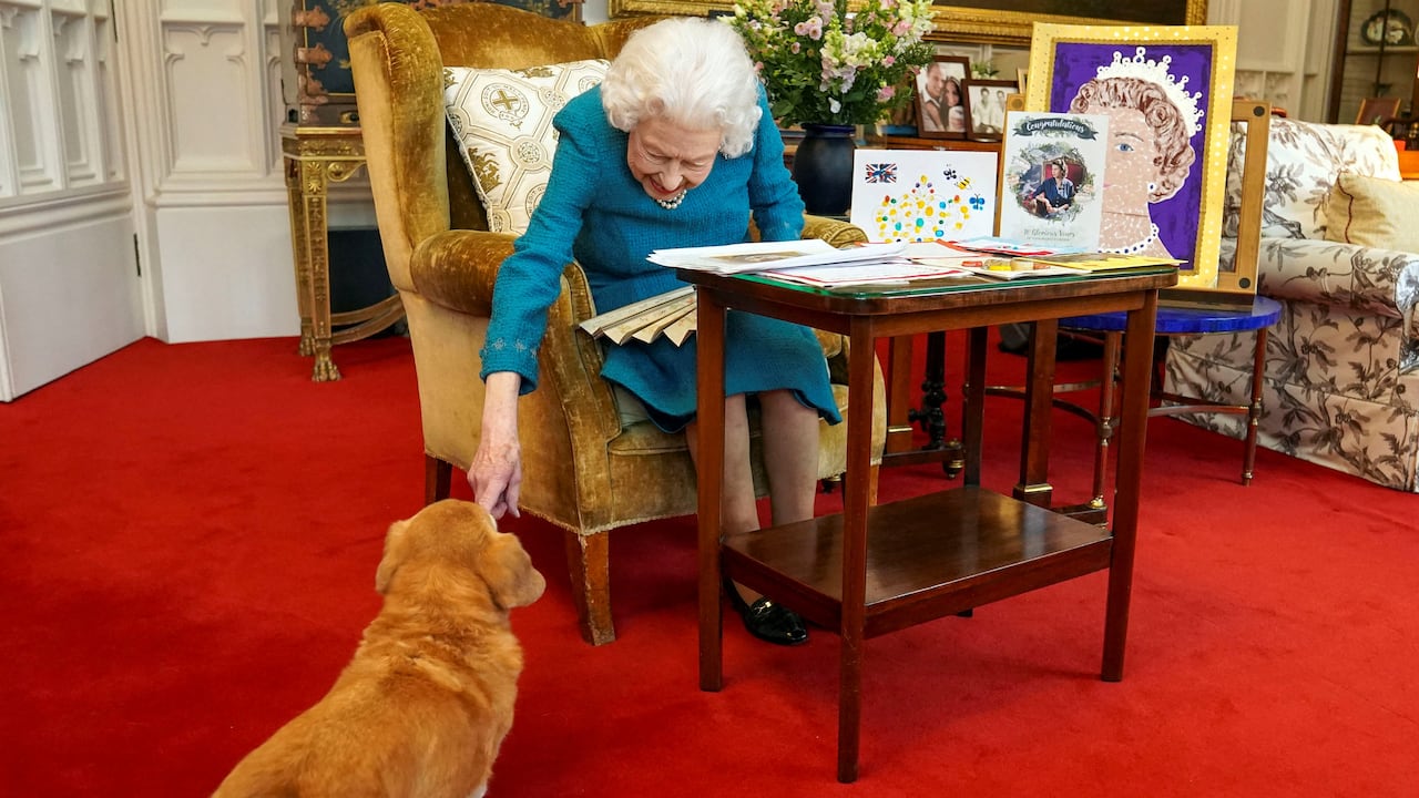 Imagen de archivo publicada en Londres el 4 de febrero de 2022 y tomada el mes pasado: la reina Isabel II de Gran Bretaña acariciando a Candy, una perra Dorgi.
