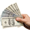 Mano sujetando dinero con billetes de cien dólares aislado sobre un fondo blanco.