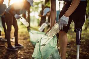 Group of multi-ethnic people, people with differing abilities , volunteers with garbage bags cleaning park area