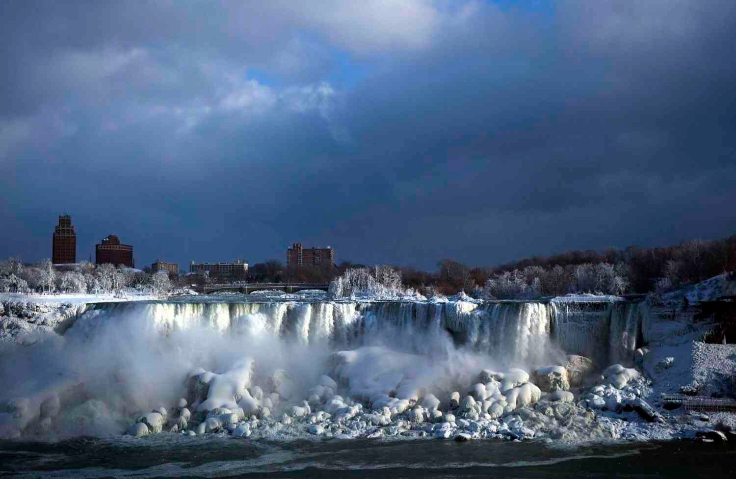 El agua fluye sobre las cataratas americanas mientras se forma hielo en esta vista desde el lado canadiense en Niagara Falls, Ontario. Casi todas las temperaturas frías del año transforman las cataratas en un país de las maravillas invernal helado.(Aaron Lynett / The Canadian Press vía AP)