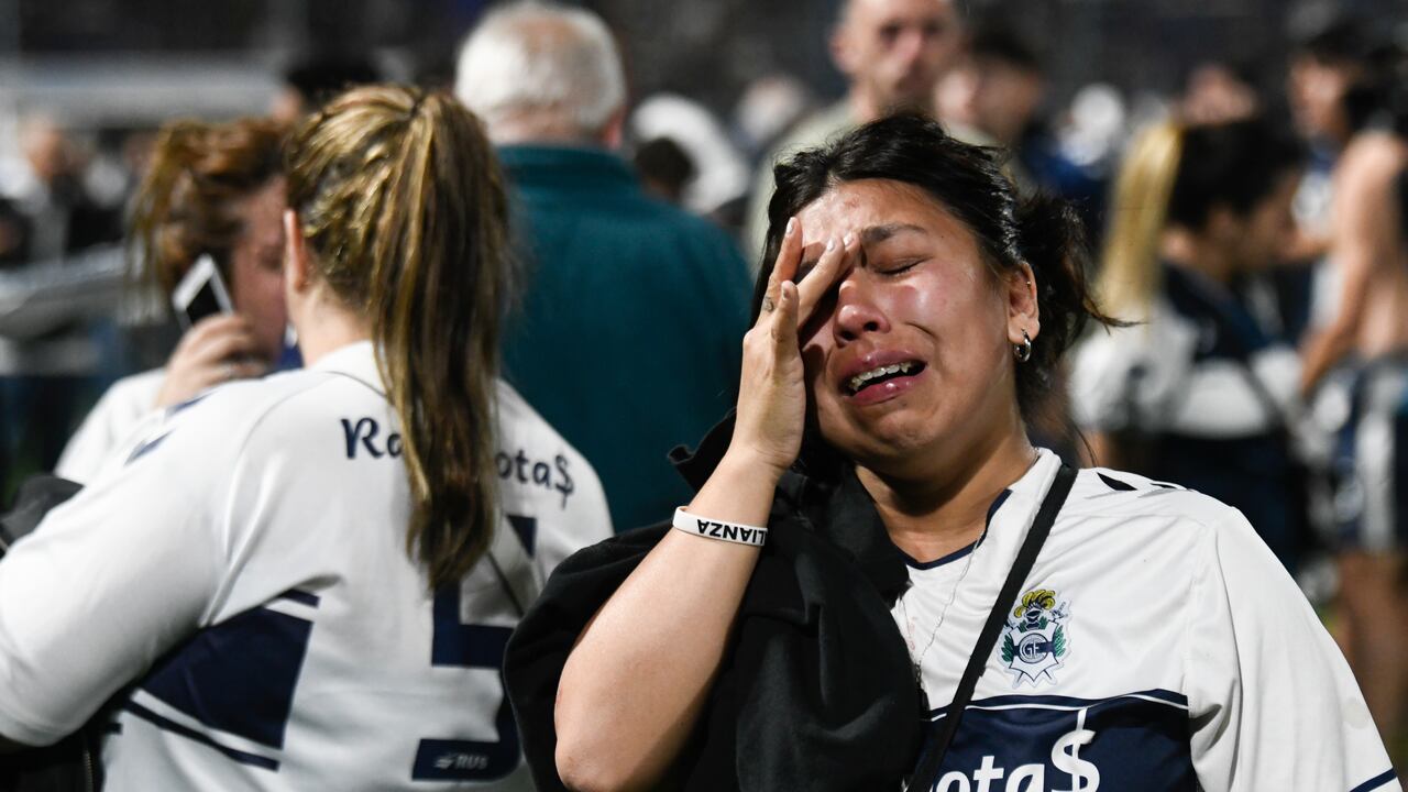 Fans of Gimnasia de La Plata react to tear gas on the field during a local tournament match between Gimnasia de La Plata and Boca Juniors in La Plata, Argentina, Thursday, Oct. 6, 2022. The match was suspended after tear gas thrown by the police outside the stadium wafted inside affecting the players as well as fans who fled to the field to avoid its effects. (AP Photo/Gustavo Garello)