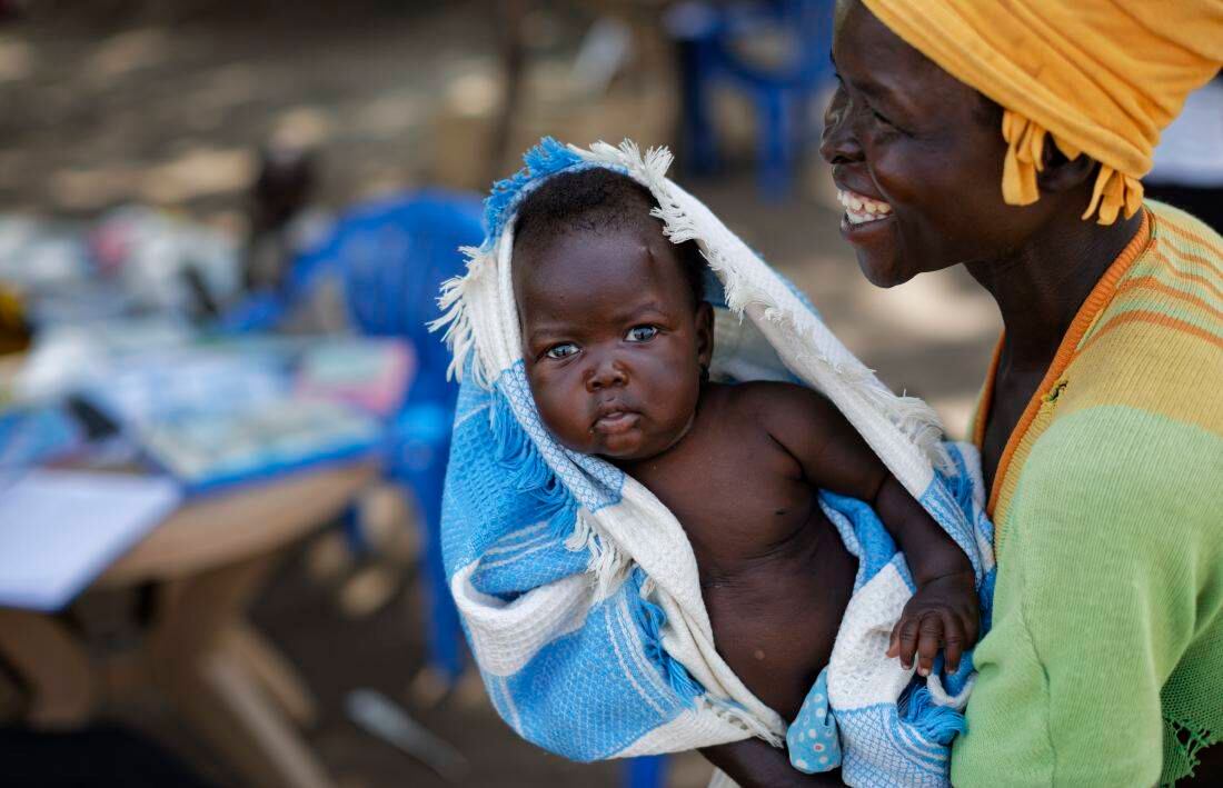 La refugiada sudanesa Betty Sakala, del estado de Central Equatoria, se ríe después de mostrar una foto de su hija Mary, de dos meses, Betty espera a que Mary sea examinada en una clínica de salud móvil dirigida por el Comité Internacional de Rescate en Bidi Bidi , Uganda (Foto de AP / Ben Curtis)