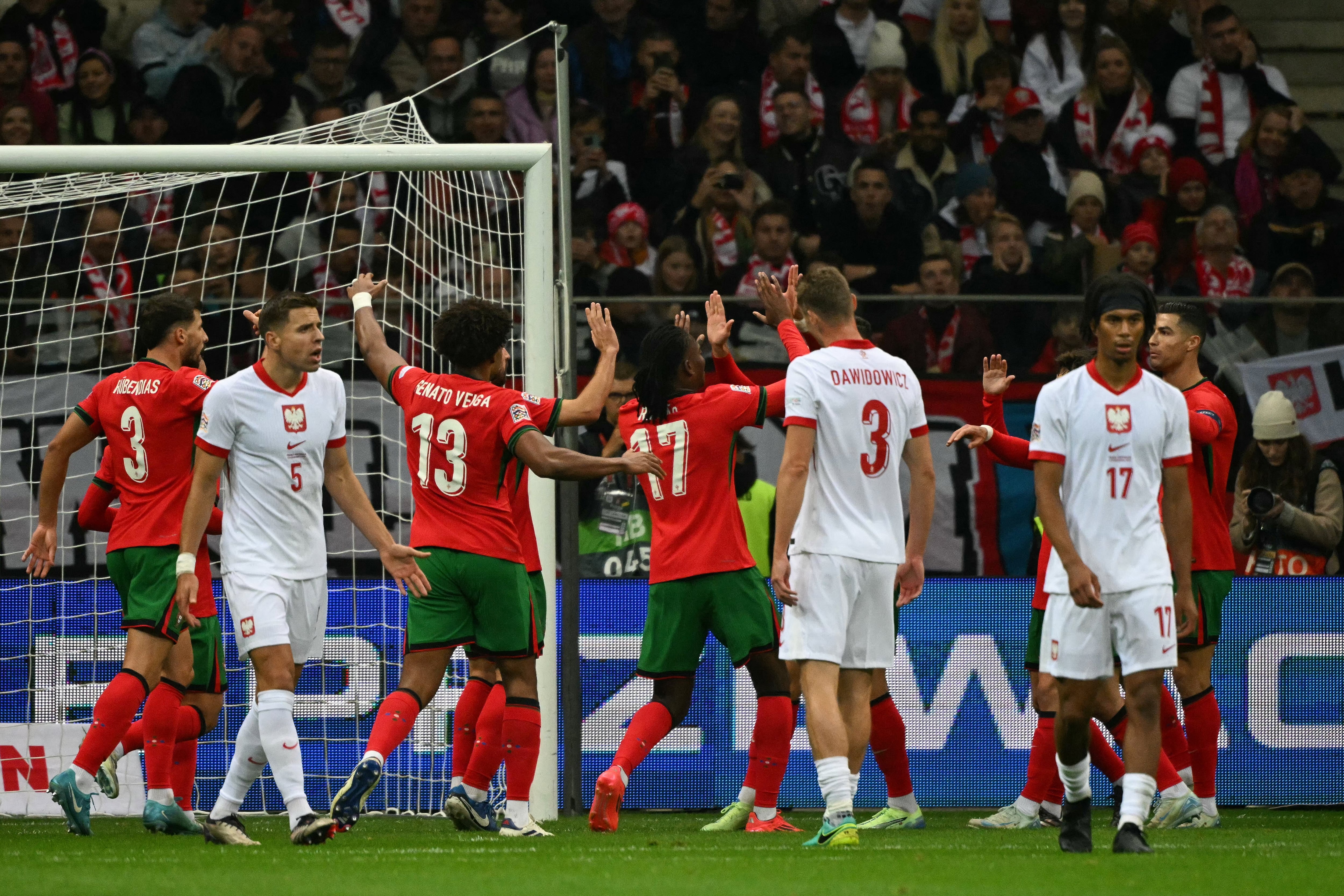 El centrocampista #10 de Portugal Bernardo Silva (oculto) celebra el gol inicial con sus compañeros de equipo durante el partido de fútbol Polonia vs. Portugal de la UEFA Nations League, Liga A Grupo A1 en el Estadio Nacional de Varsovia, Polonia, el 12 de octubre de 2024.