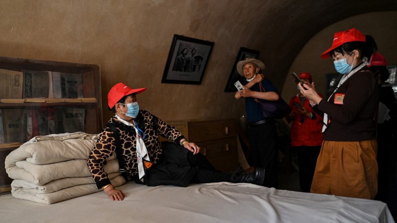 Esta foto tomada durante un tour de medios organizado por el gobierno muestra a un turista posando en una cama para una foto en la antigua residencia del ex líder chino Mao Zedong en el Sitio Revolucionario Yangjialing en Yan'an, la sede del Partido Comunista Chino desde 1936 hasta 1947, en la provincia de Shaanxi el 10 de mayo de 2021, antes del centenario de la fundación del partido en julio. Foto de Hector RETAMAL / AFP